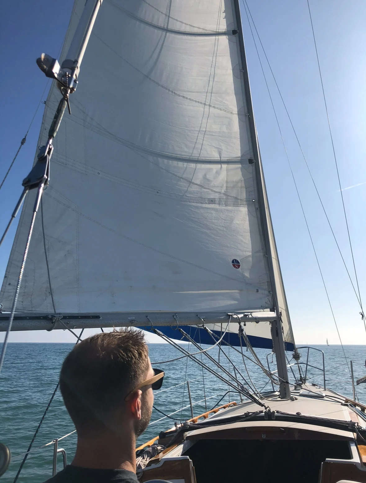 Me in the cockpit of a sailboat under full sail on open water
