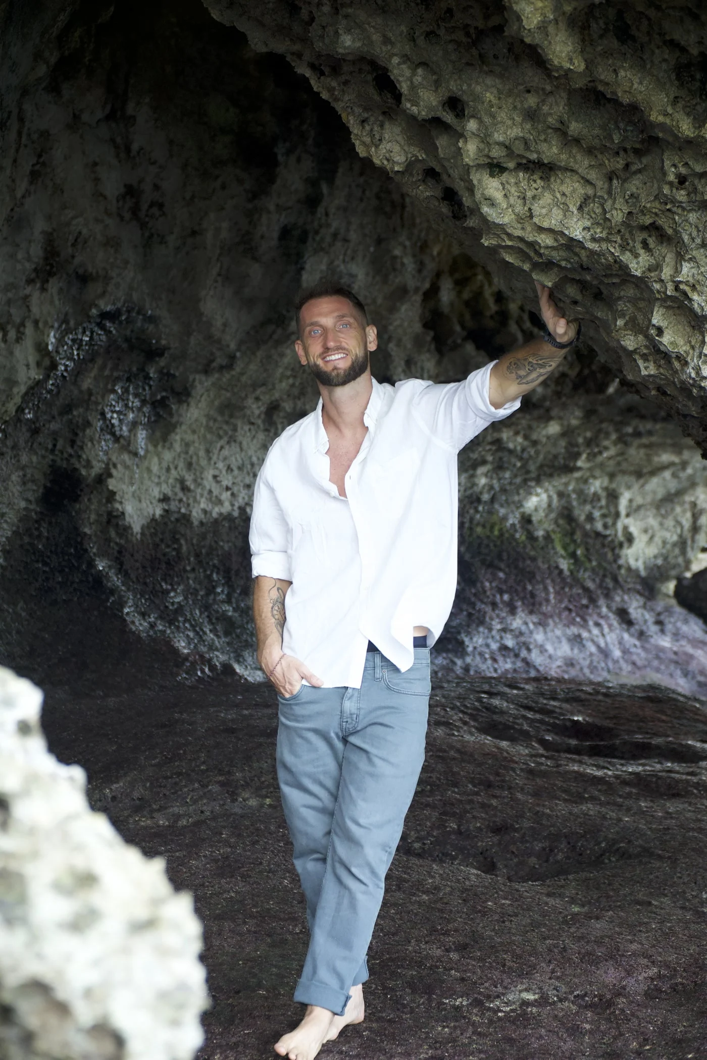 Me standing barefoot in a sea cave in Uluwatu, Bali, one hand resting on the rock